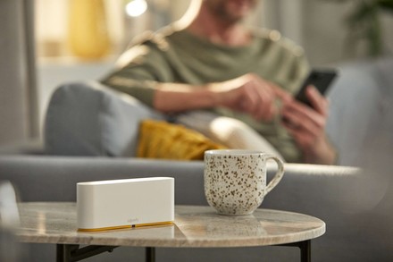  Na stoliku stoi TaHoma Somfy – centralka smart home. W tle mężczyzna korzysta ze smartfona.